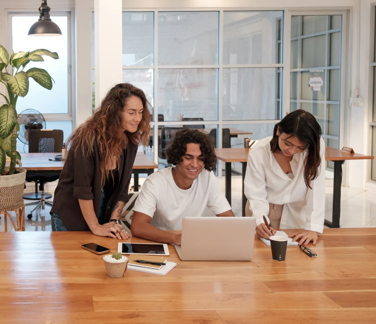 Tres personas del equipo revisando juntas información frente a un portátil